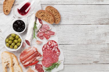 Salam, dilimlenmiş jambon, sosis, jambon, pastırma, tost, zeytin. Et meze tabağı ve ahşap masa üzerinde kırmızı şarap. Kopya alanı ile Üstten Görünüm