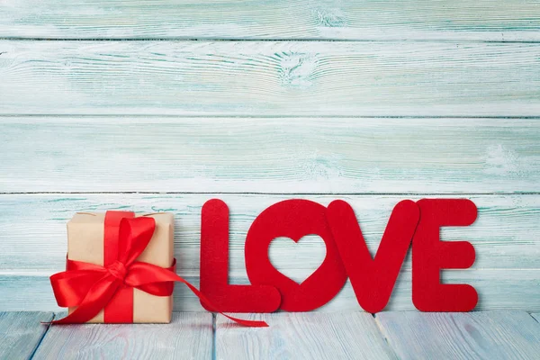 Sevgililer günü tebrik kartı hediye kutusu ve aşk kelime üzerinde ahşap arka plan ile. Boşlukla 