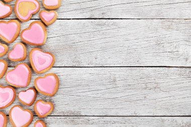 Sevgililer günü tebrik kartı kalp ile gingerbread çerezleri üzerinde ahşap arka plan şeklinde. Boşlukla 