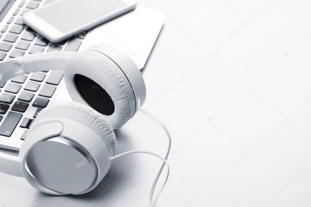 Headphones over laptop on wooden desk table. Music concept. View with copy space. Toned