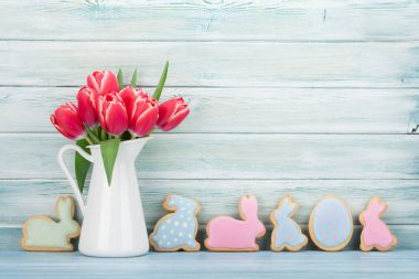 Kırmızı lale ve Paskalya gingerbread çerezleri ahşap duvar önünde. Paskalya tebrik kartı ile yer