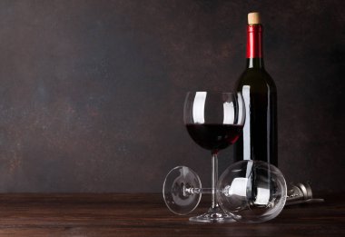 Kırmızı şarap şişesi ve tahta duvar önünde bardak. Metniniz için kopya alanı ile