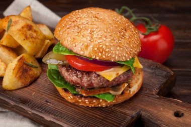 Lezzetli ızgara ev yapımı biftek, domates, peynir, salatalık ve marullu hamburger.