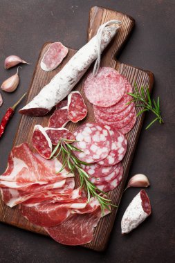 Salam, dilimlenmiş jambon, sosis, salam, pastırma. Et meze tabağı taş masada. Üstten Görünüm