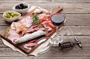 Salam, dilimlenmiş jambon, sosis, jambon, pastırma, tost, zeytin. Ahşap masa et meze tabağı ve kırmızı şarap