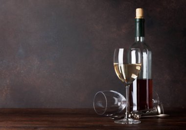 Beyaz şarap şişesi ve tahta duvar önünde bardak. Kopya alanı ile 