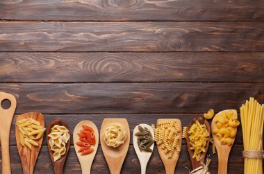Çeşitli makarna üzerine kaşık ahşap arka plan üzerinde. Pişirme kavramı. Üstten Görünüm ile tarifi için yer