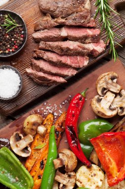 Izgara sebze ve sığır eti biftek ahşap masa üzerinde kesme tahtası üzerinde. Üstten Görünüm
