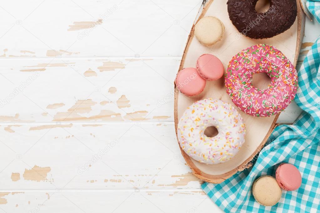 Macaroons and donuts on wooden table. Top view with space for your text