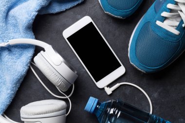 Spor ayakkabı, kulaklık, smartphone, su şişesi ve havlu ile fitness kavramı arka plan. Kopya alanı ile Üstten Görünüm