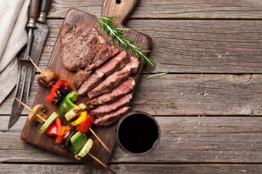 Izgara sebze ve sığır eti biftek ahşap masa üzerinde kesme tahtası üzerinde. Kopya alanı ile Üstten Görünüm