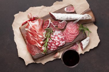 Salam, jambon, sosis, jambon, pastırma ve kırmızı şarap cam dilimlenmiş. Et meze tabağı taş masada. Üstten Görünüm