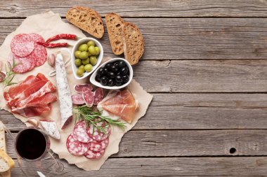 Salam, jambon, sosis, jambon, pastırma, zeytin, ekmek ve kırmızı şarap cam dilimlenmiş. Ahşap masa üzerinde et meze tabağı. Kopya alanı ile Üstten Görünüm