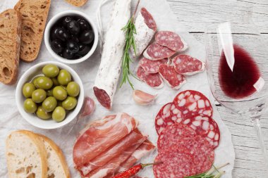 Salam, dilimlenmiş jambon, sosis, jambon, pastırma, tost, zeytin. Et meze tabağı ve ahşap masa üzerinde kırmızı şarap. Üstten Görünüm