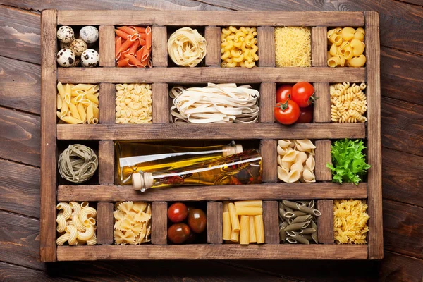 Various pasta in wooden box and condiments. Cooking concept. Top view