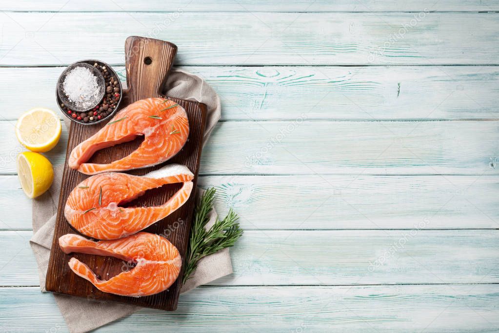 Raw salmon fish steaks with spices cooking on cutting board. Top view with space for your text