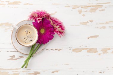 Kahve Kupası ve gerbera çiçekleri buketi beyaz tahta masada. Metin alanı olan Üstten Görünüm