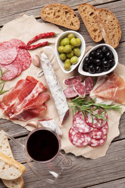 Salam, jambon, sosis, jambon, pastırma, zeytin, ekmek ve kırmızı şarap cam dilimlenmiş. Ahşap masa üzerinde et meze tabağı. Üstten Görünüm