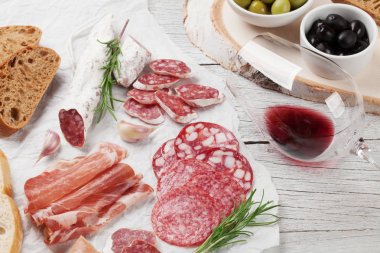 Salam, jambon, sosis, jambon, pastırma, zeytin, ekmek ve kırmızı şarap cam dilimlenmiş. Ahşap masa üzerinde et meze tabağı