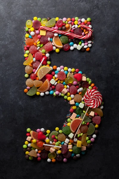 Number five made from sweet candies on dark background. Greeting card concept