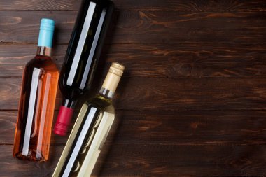 Kırmızı, pembe ve beyaz şarap şişeleri ahşap masa üzerinde. Kopya alanı ile Üstten Görünüm