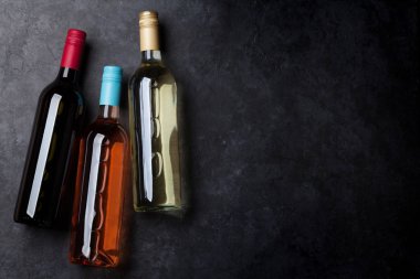 Kırmızı, pembe ve beyaz şarap şişeleri taş masada. Kopya alanı ile Üstten Görünüm