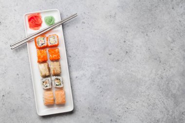 Japon suşi seti. Sashimi, maki ruloları. Taş arka plan üzerinde plaka üzerinde. Metninizin kopya alanıyla üst görünüm düz yatıyordu