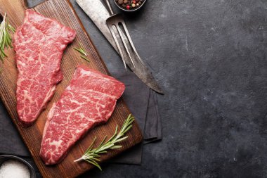 Tahta üzerinde çiğ mermer biftek. Üst görünüm düzlüğü kopyalama alanı ile yatıyordu