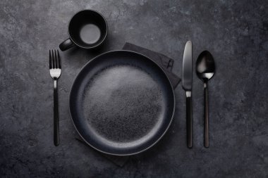 Boş tabak, bardak, çatal, kaşık ve bıçak. Siyah mutfak gereçleri taş masaya dizilmiş. Üst görünüm düzlüğü kopyalama alanı ile yatıyordu