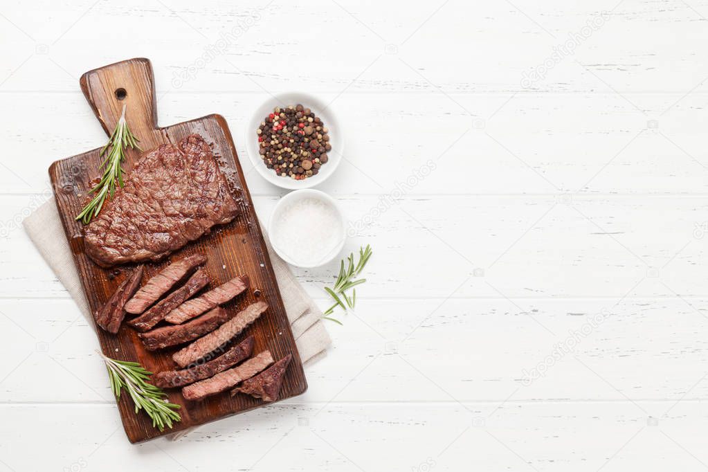 Grilled beef steak on wooden board. Top view flat lay with copy space