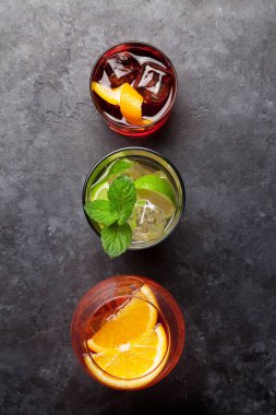 Taş masada üç klasik kokteyl bardağı. Negroni, aperol spritz ve mojito. Kopyalama alanı olan üst görünüm. Düz yatıyordu