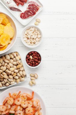 Ahşap arka planda bira atıştırmalıkları. Fındık, cips, sosis ve karides. Düz yatıyordu. Kopyalama alanı ile üstte görünüm