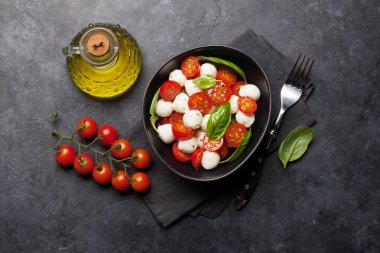 Kiraz domates, mozzarella, fesleğen yaprakları ve çeşni ile taze klasik caprese salatası. Düz yatıyordu. Üstte görüntü