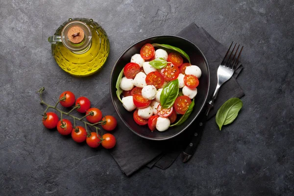 Kiraz domates, mozzarella, fesleğen yaprakları ve çeşni ile taze klasik caprese salatası. Düz yatıyordu. Üstte görüntü