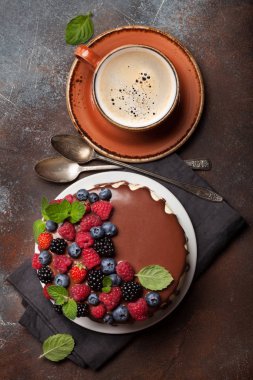 Böğürtlenli çikolatalı kek ve kahve fincanı. Taş masada. Üst görünüm düzlüğü
