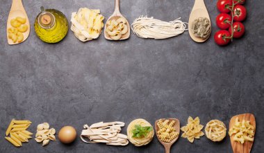 Kaşıklar ve yemek malzemeleriyle çeşitli makarnalar. Üst görünüm düzlüğü kopyalama alanı ile yatıyordu