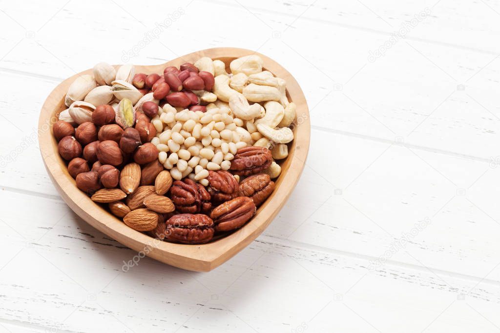 Various nuts selection: peanuts, hazelnuts, chestnuts, walnuts, pistachio and pecans on wooden table. With space for your text