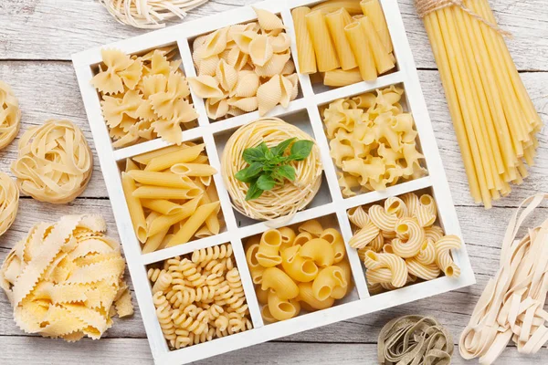 Various pasta in wooden box. Top view flat lay