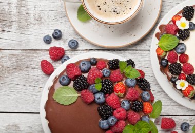 Çikolatalı kek ve çilekli cheesecake ve kahve fincanı. Kopya alanı olan ahşap masada. Üst görünüm düzlüğü