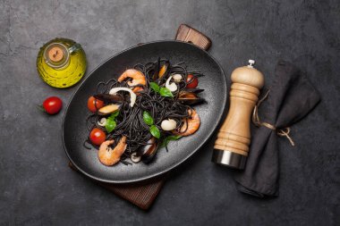 Deniz ürünleri, domates ve fesleğenli siyah spagetti makarna. Üst görünüm düzlüğü