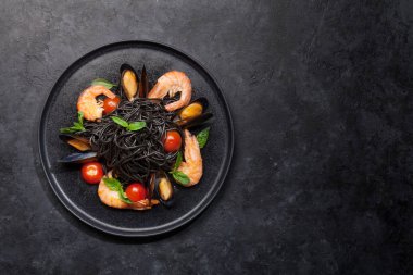 Deniz ürünleri, domates ve fesleğenli siyah spagetti makarna. Üst görünüm düzlüğü kopyalama alanı ile yatıyordu
