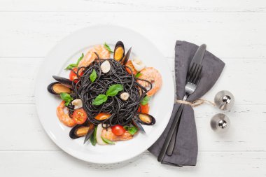 Deniz ürünleri, domates ve fesleğenli siyah spagetti makarna. Üst görünüm düzlüğü