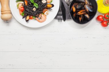 Deniz ürünleri, domates ve fesleğenli siyah spagetti makarna. Üst görünüm düzlüğü kopyalama alanı ile yatıyordu