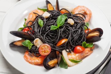 Deniz ürünleri, domates ve fesleğenli siyah spagetti.