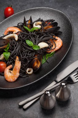 Deniz ürünleri, domates ve fesleğenli siyah spagetti.
