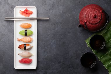 Japon suşi seti. Sashimi, maki rulo ve yeşil çay. Metin için boşluk ile taş arka plan üzerinde plaka üzerinde. Üst görünüm düz yatıyordu