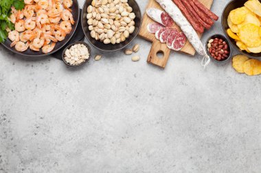 Taş zeminde bira atıştırmalıkları. Fındık, cips, sosis ve karides. Kopyalama alanı ile üstte görünüm