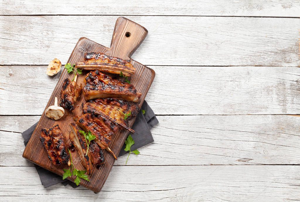 Barbecue beef ribs with bbq sauce sliced on a wooden board. Top view flat lay with copy space