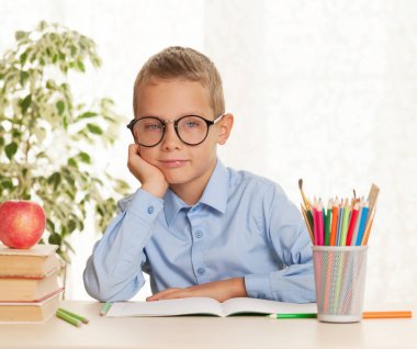 Genç okul çocuğu masada oturuyor ve ödev yapıyor. Temel eğitim konsepti