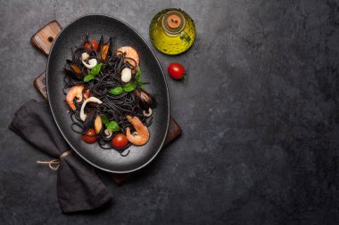 Deniz ürünleri, domates ve fesleğenli siyah spagetti makarna. Üst görünüm düzlüğü kopyalama alanı ile yatıyordu